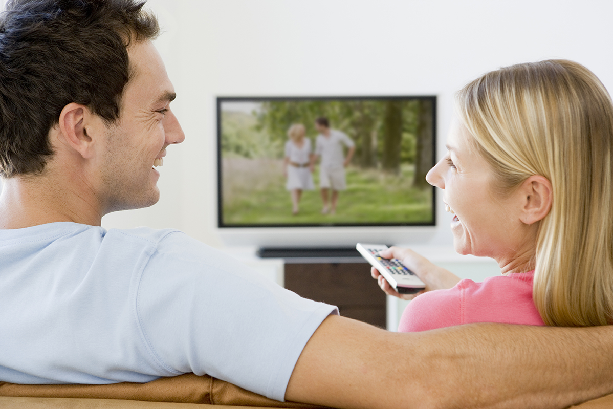 Couple in living room watching television smiling